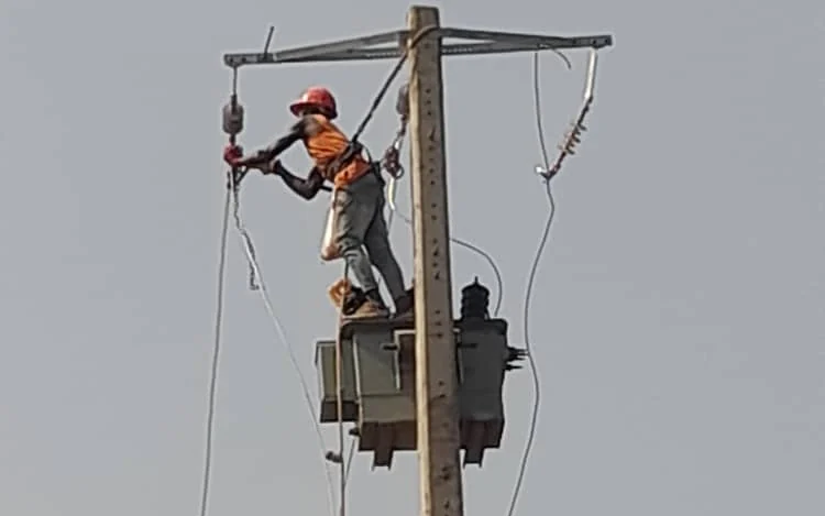 Technicien SETCO installant un poste de transformation sur poteau